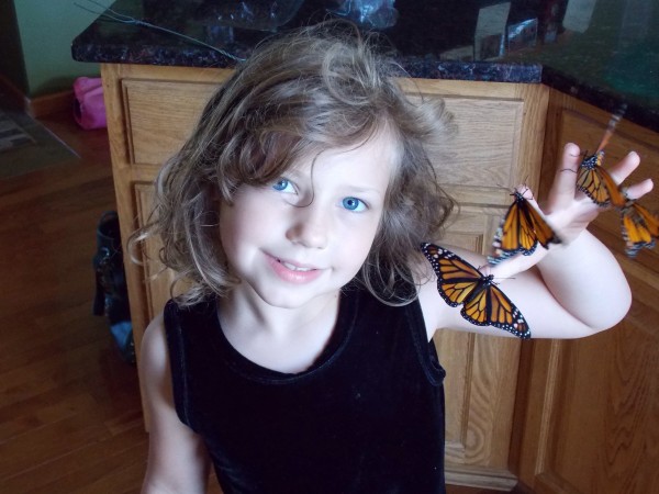 Image of girl holding a monarch butterfly.