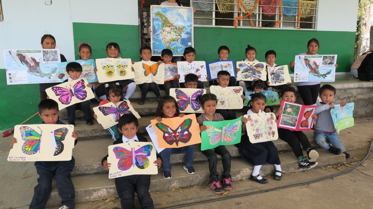 Kindergarteners hold artwork of monarch butterflies