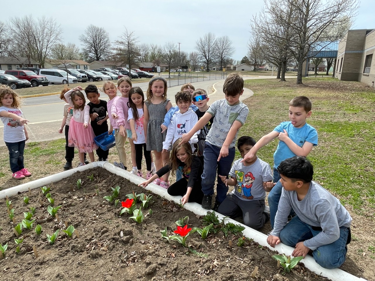 Kids pose for a photo with two red blooming tulips