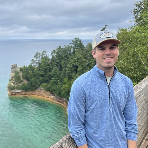 Jacob Swanson standing in front of a rock formation on Lake Superior