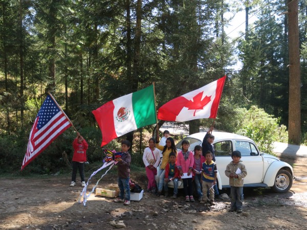 Children in Mexico holding flags of Mexico, U.S., and Canada.