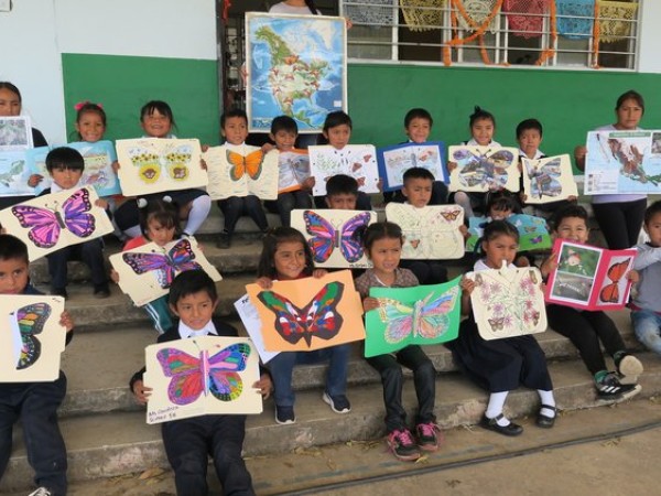 Kindergarteners hold artwork of monarch butterflies